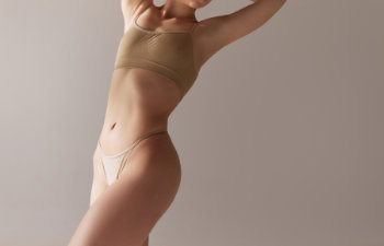beautiful female body in beige underwear against grey studio background